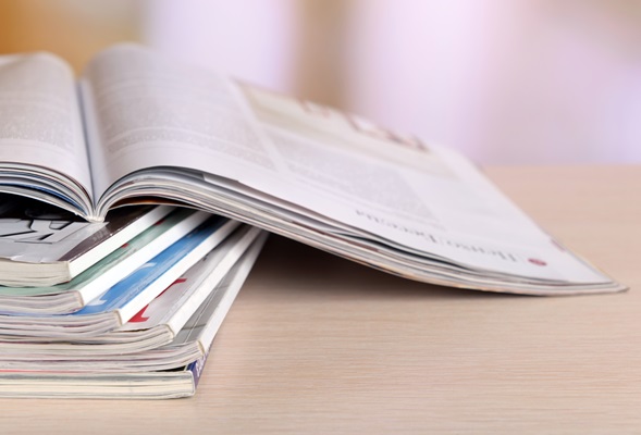 Magazines on wooden table on bright background
